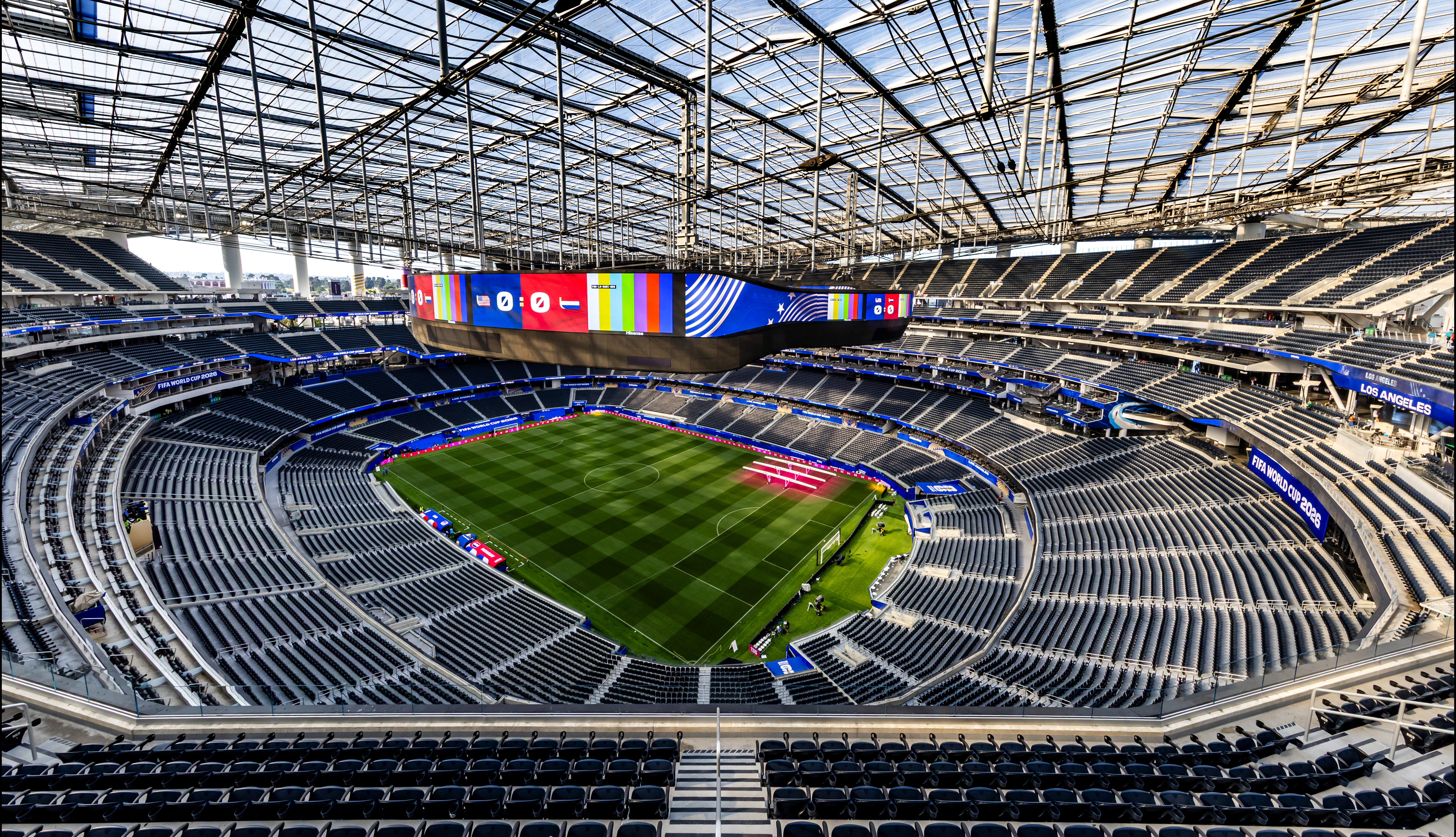 Modern, empty stadium with a green sports field and a large jumbotron.