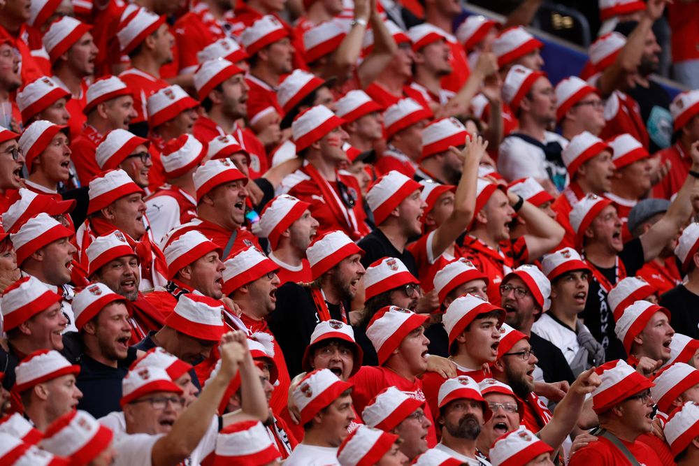 A large crowd of enthusiastic fans wearing red and white striped bucket hats at an event.