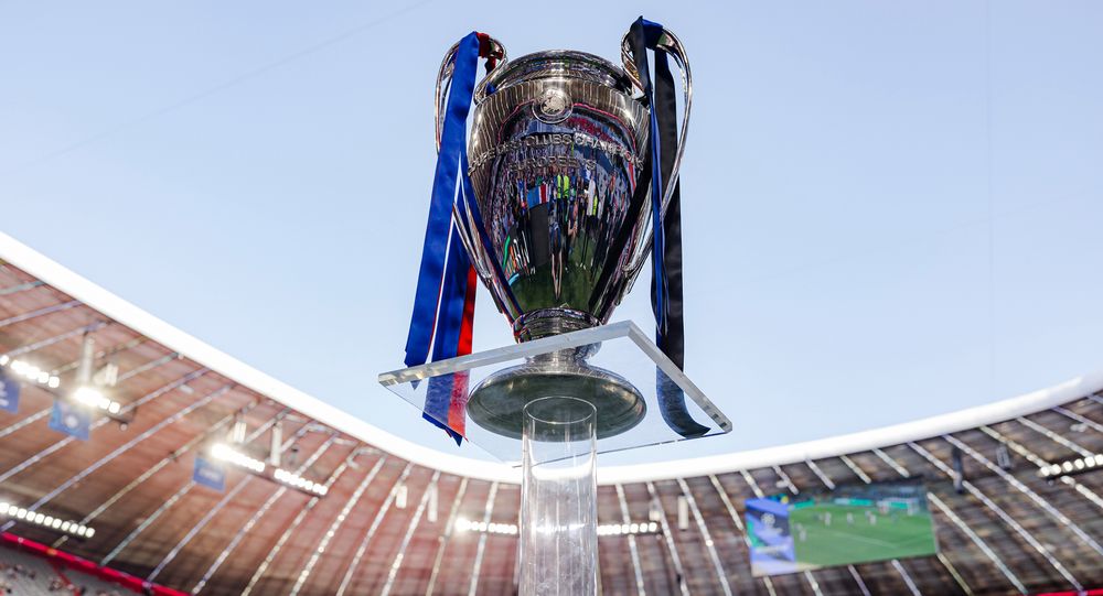 UEFA Champions League trophy with blue and red ribbons displayed in a stadium.