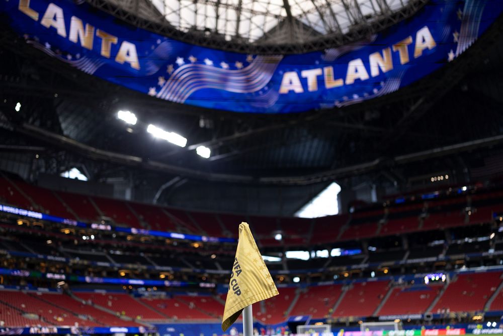 Yellow corner flag in a stadium with 'ATLANTA' displayed on large screens.