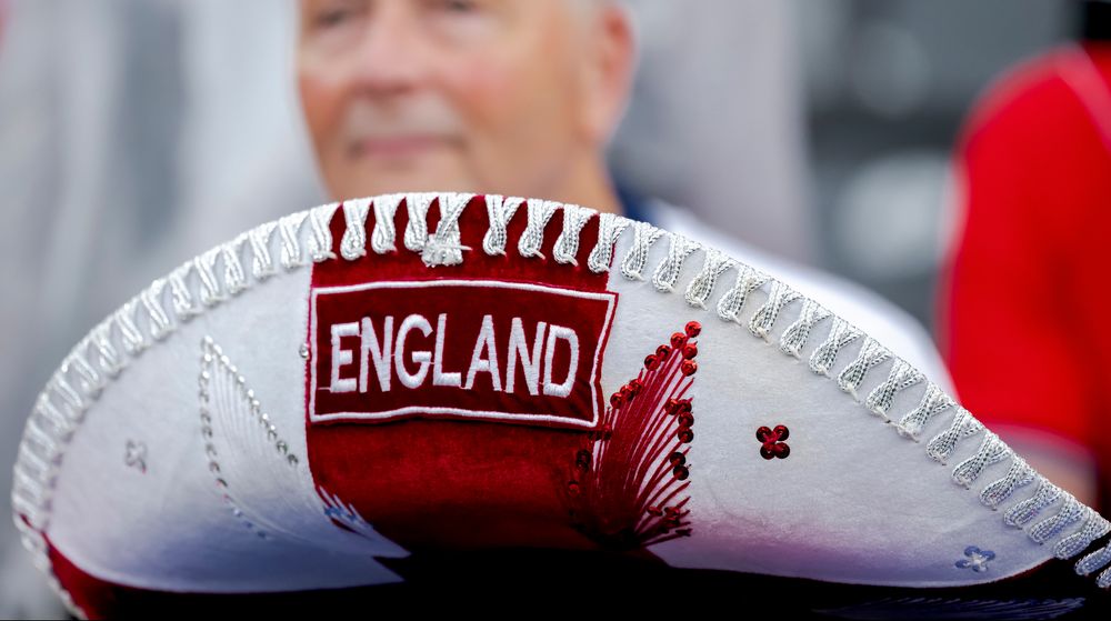 White and red sombrero with 'ENGLAND' embroidered, a blurred person in the background.