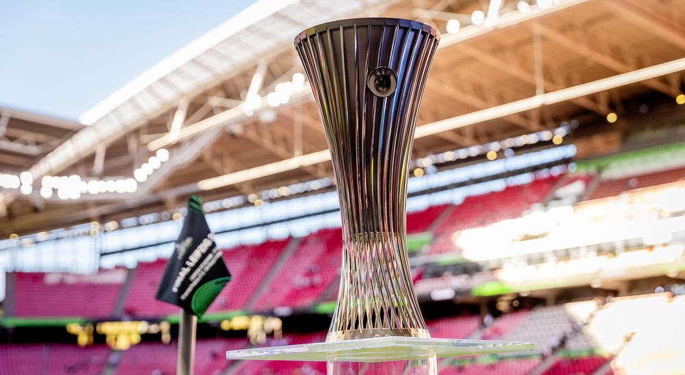 A close-up of the UEFA Europa Conference League trophy in a bright stadium.