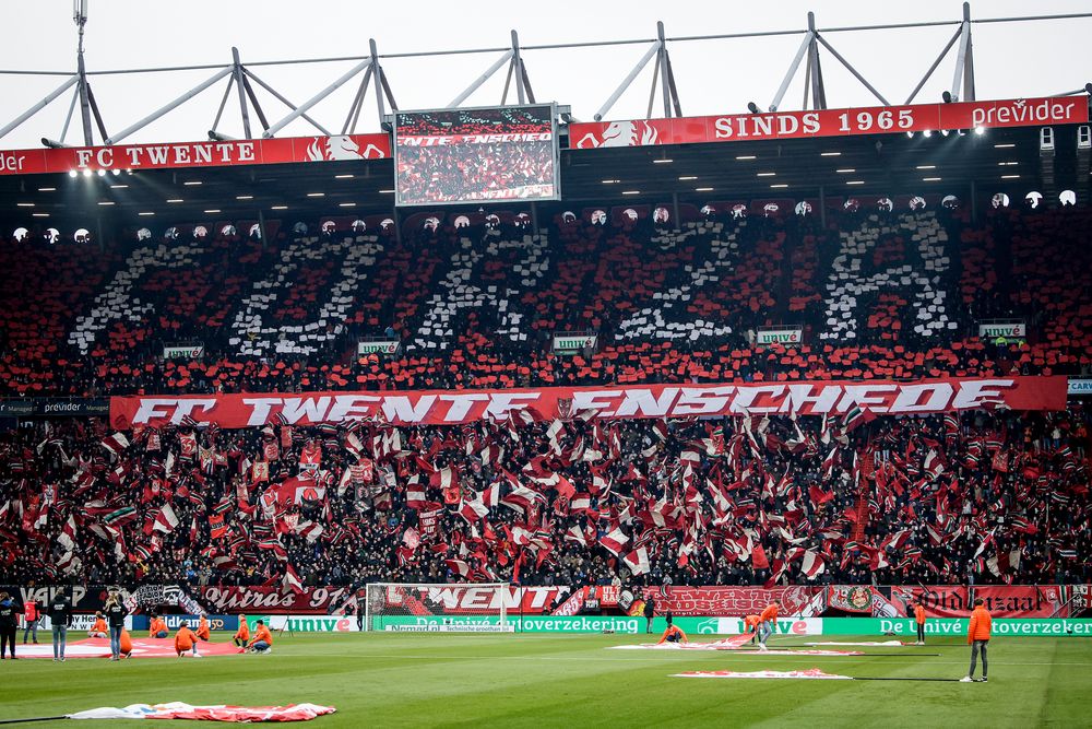 Stadium fans use red and white cards to spell "SODA" and "FC Twente Enschede" across the stands.
