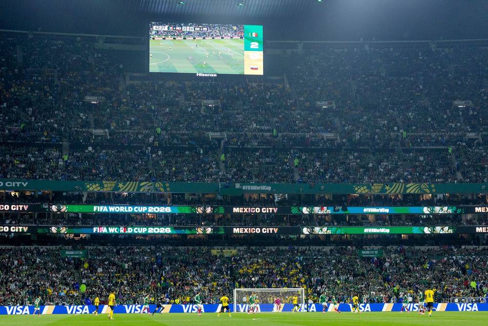 Night view of a packed stadium with scoreboard showing soccer and FIFA World Cup 2026.