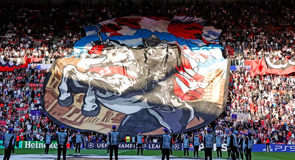 Fans unfurl a giant tifo banner featuring a powerful animal design in a packed stadium.