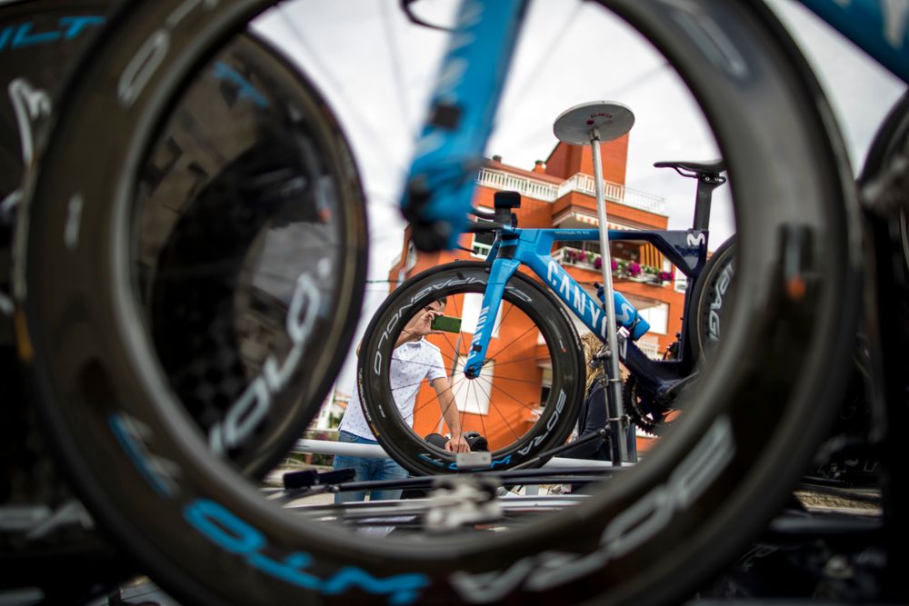 Aerodynamic blue racing bicycle seen through the foreground wheel of another bicycle.