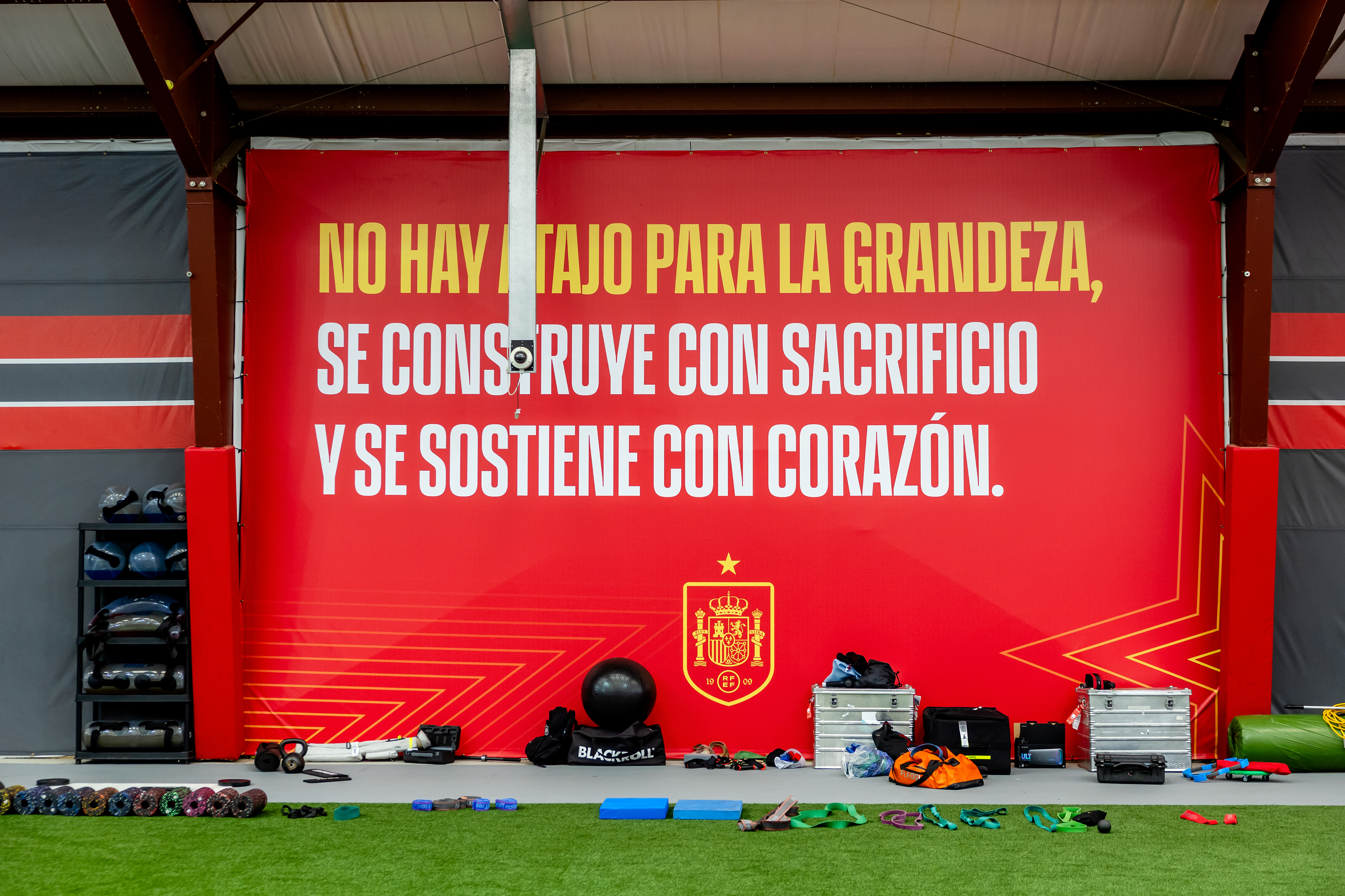 Motivational banner in a gym: 'No shortcut to greatness, built with sacrifice and heart'.